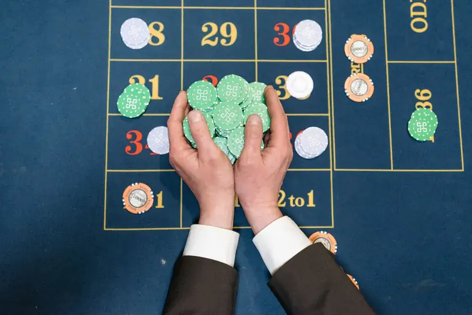 Hands in a suit holding poker chips on a casino gaming table.